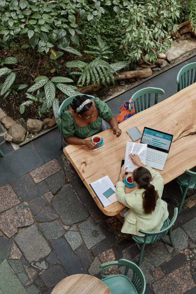 Vertical top down shot of two successful businesswomen discussing documents in cafe